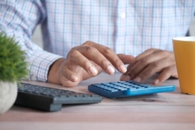 investimentos isentos de ir: homem usando calculadora azul