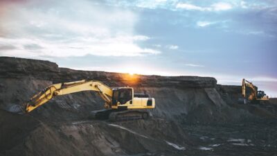 como investir em terras raras: escavadeira escavando uma terra