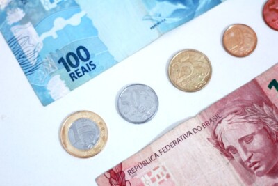 quanto rende 100 mil no cdb por mês: notas e moedas sobre uma mesa branca