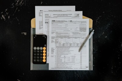 saída fiscal: Formulários fiscais com calculadora e caneta em superfície escura