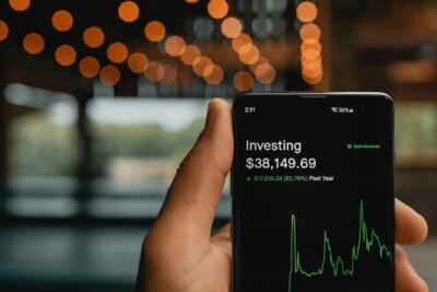buy and hold: uma pessoa segurando um telefone celular com um gráfico de ações nele